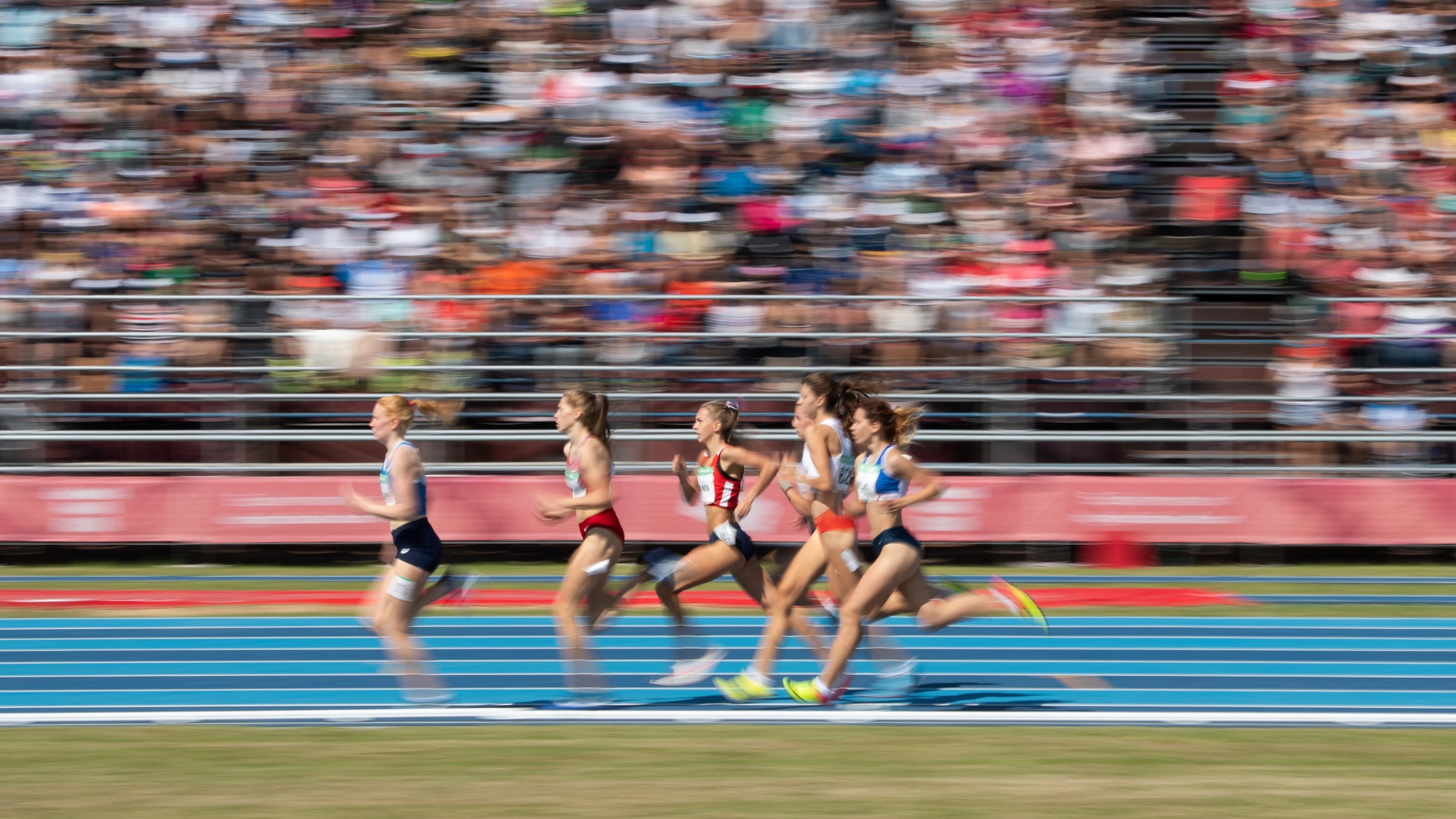 Athletes racing on track with audience behind