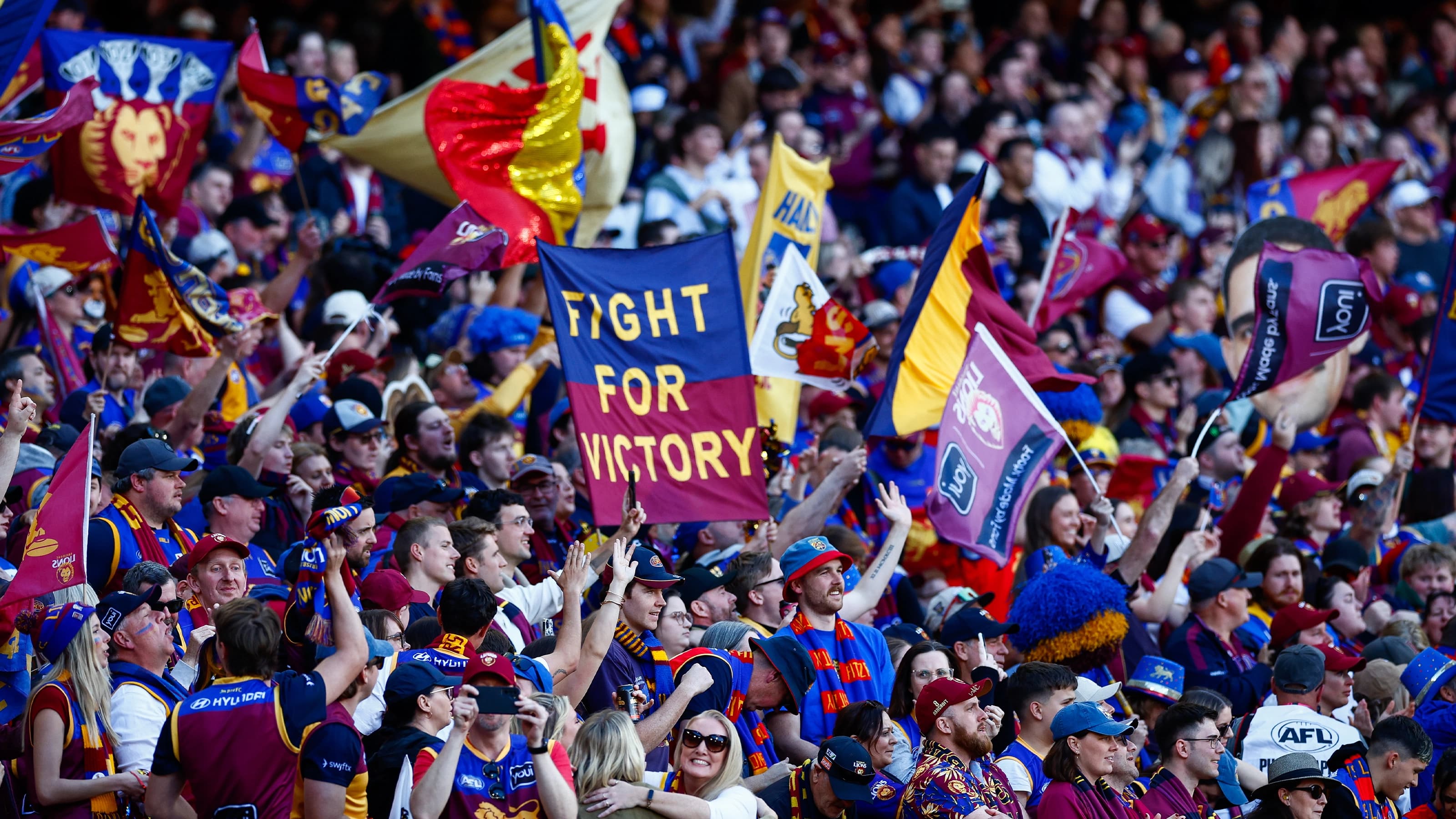 Brisbane Lions fans cheering in the stands with flags